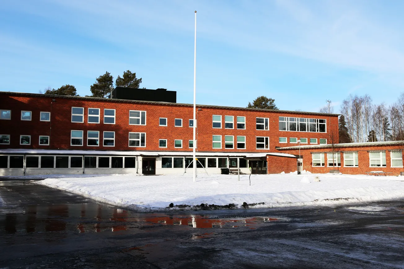 En röd tegelbyggnad med en flaggstång framför sig.