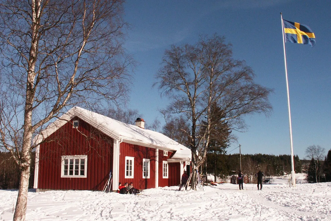 Röd stuga i vinterlandskap.