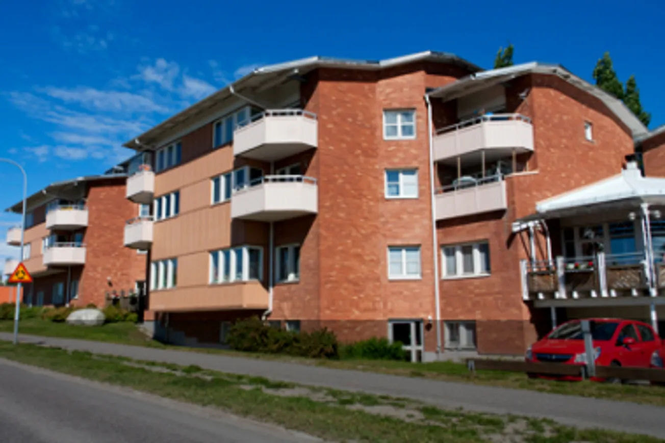 En röd bil parkerad framför en röd tegelbyggnad.