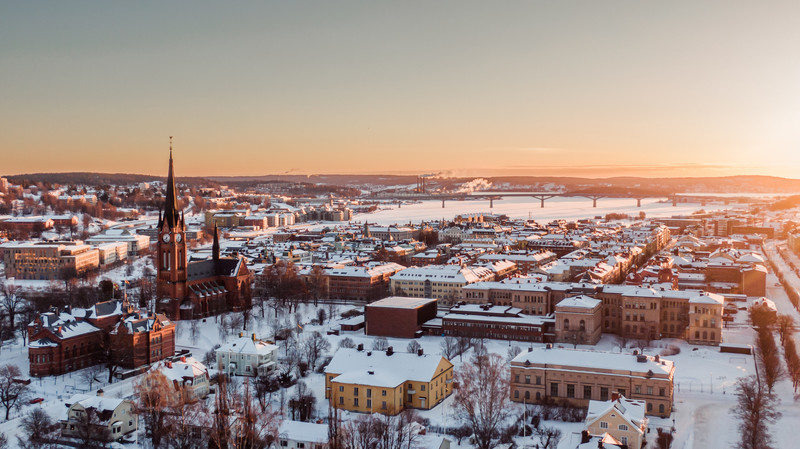 Bild över snötäckta hustak av Sundsvalls stenstad med Sundsvallsbron och inloppet av Sundsvallsfjärden i bakgrunden.