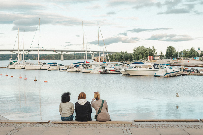 Tre personer sitter vid småbåtshamnen i Sundsvall. Fotograf Evelina Ytterbom.
