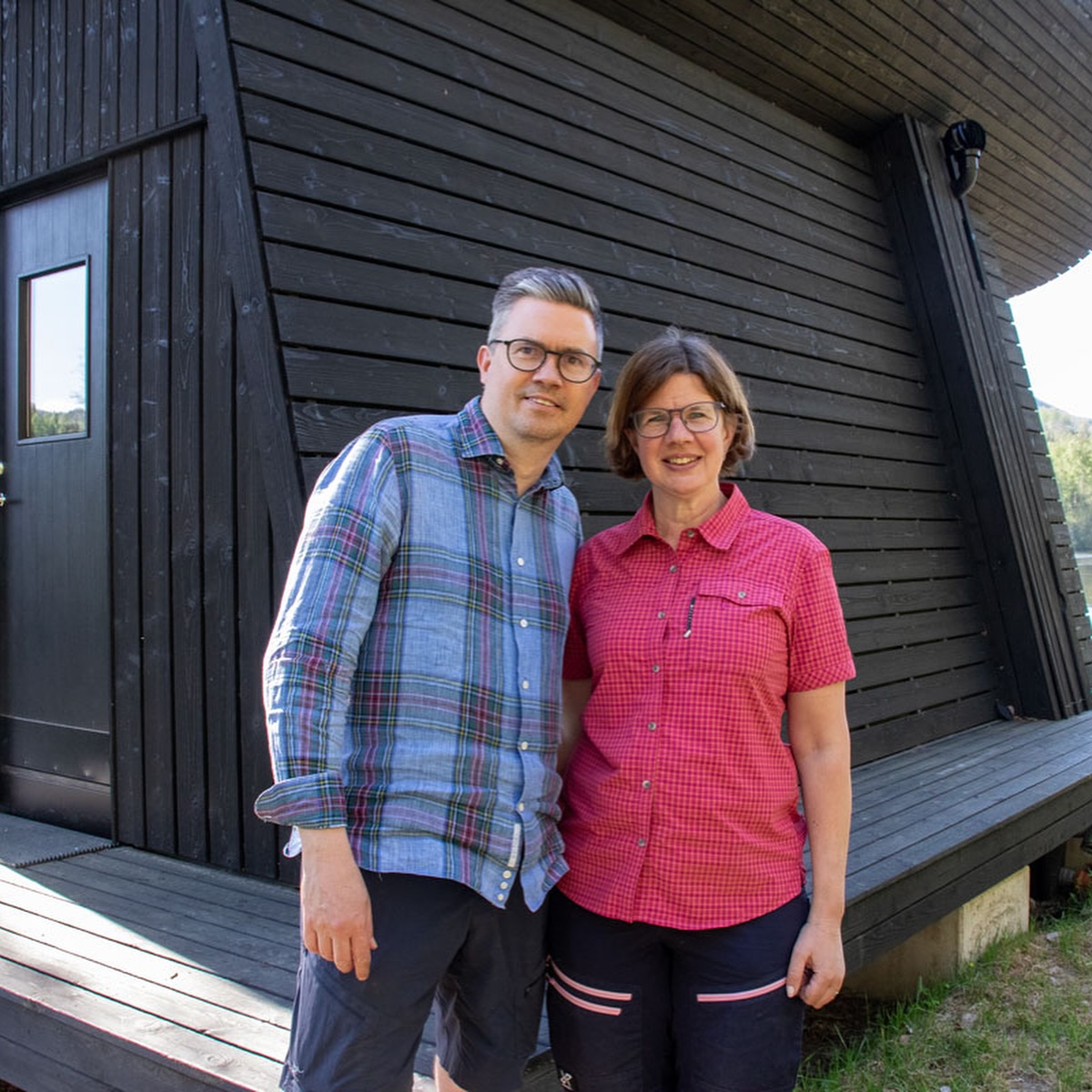 En man och en kvinna står framför en byggnad i trä