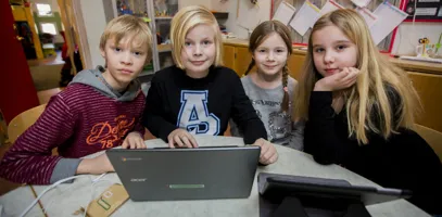 En grupp grundskoleelever sitter och jobbar vid en bärbar dator.