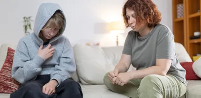 Två personer sitter på en soffa i ett vardagsrum.