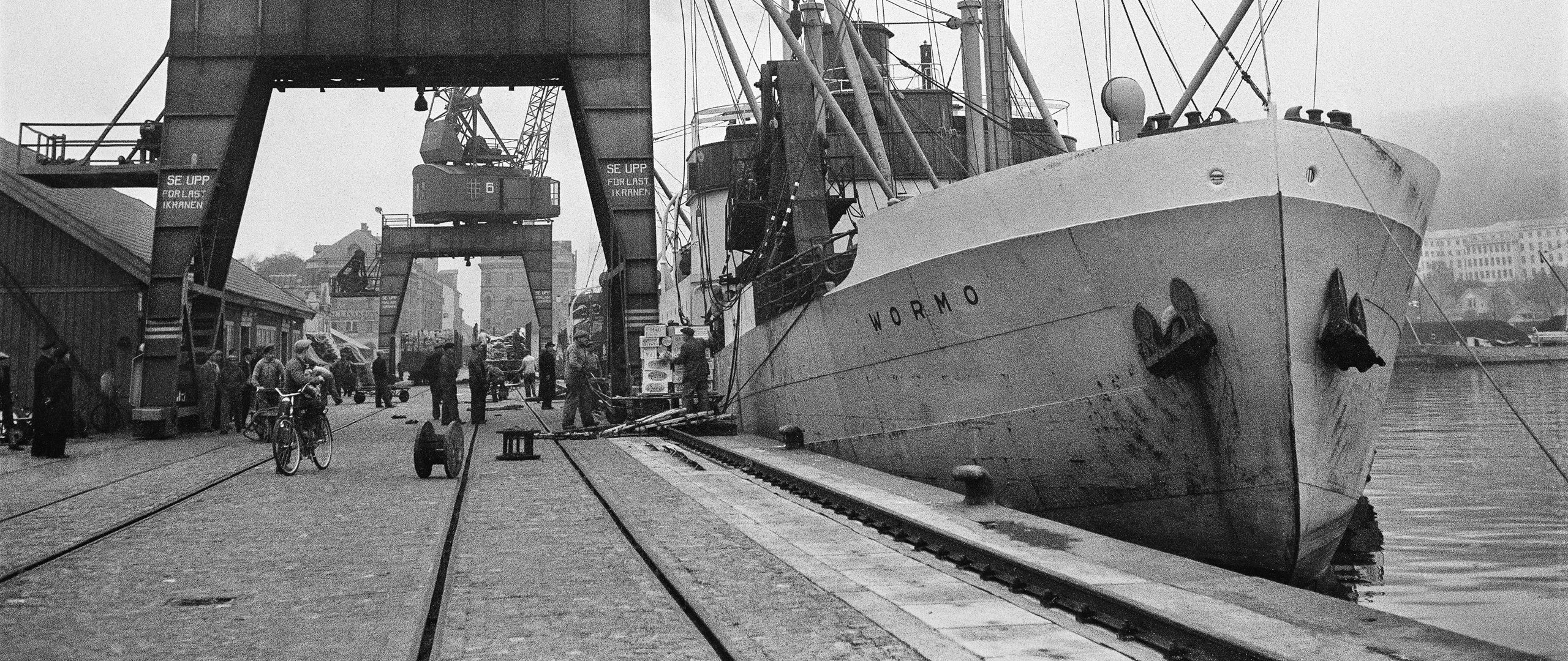 Fartyg i hamn. Bredvid står två av hamnens stora lastkranar.