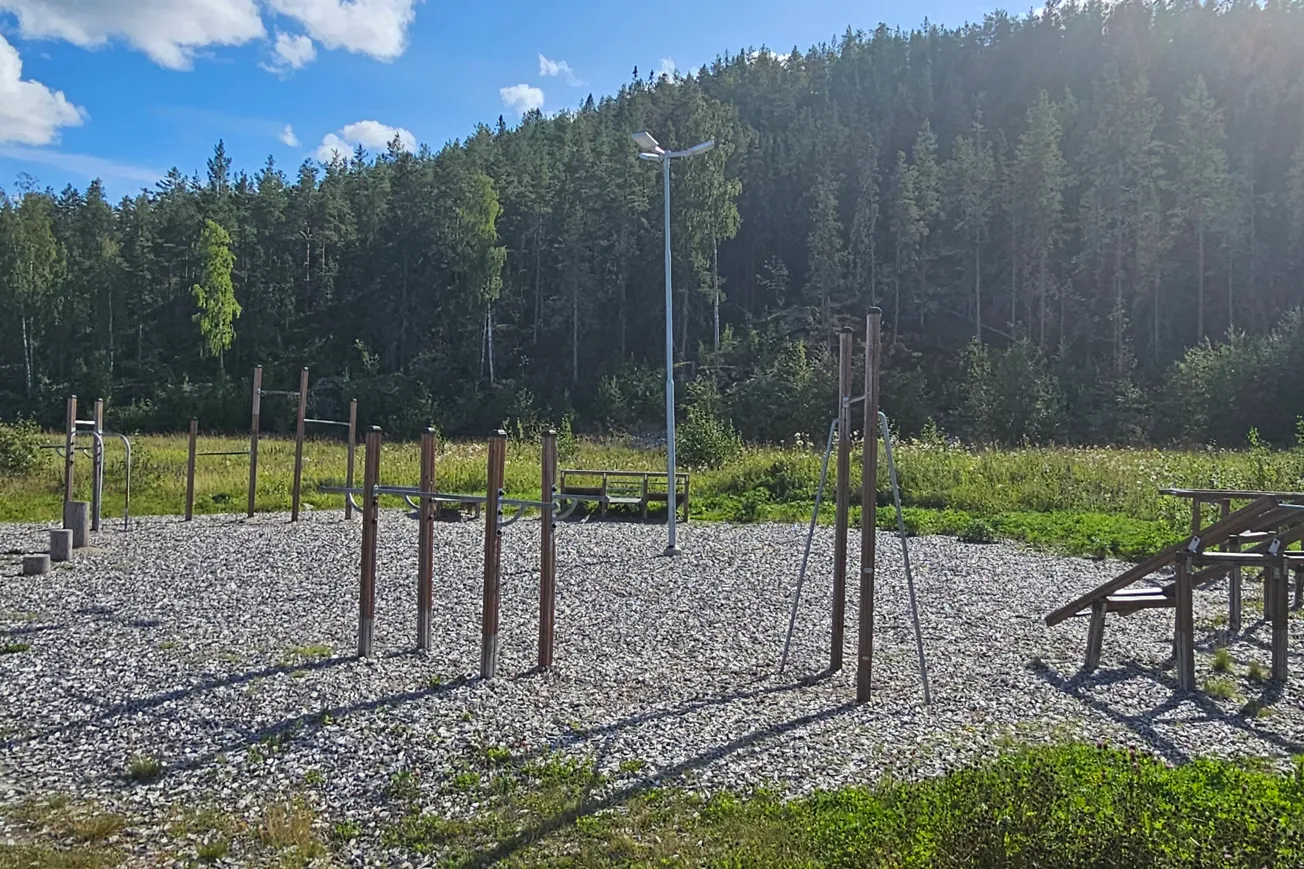 Utegym med träningsredskap, skog i bakgrunden.