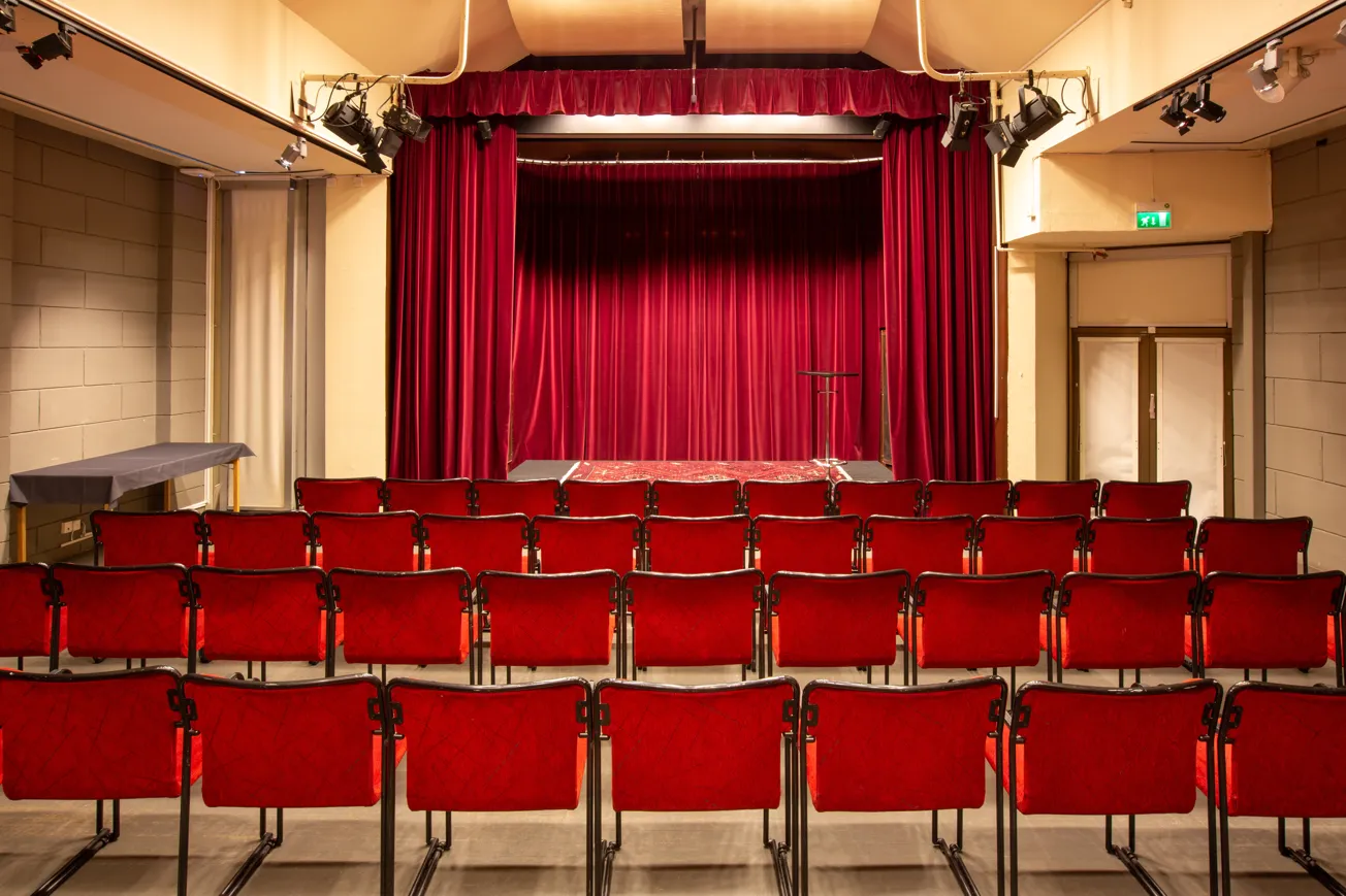 Ett stort rum med röda stola, avsett för föreläsningar, barnteater och filmvisning.