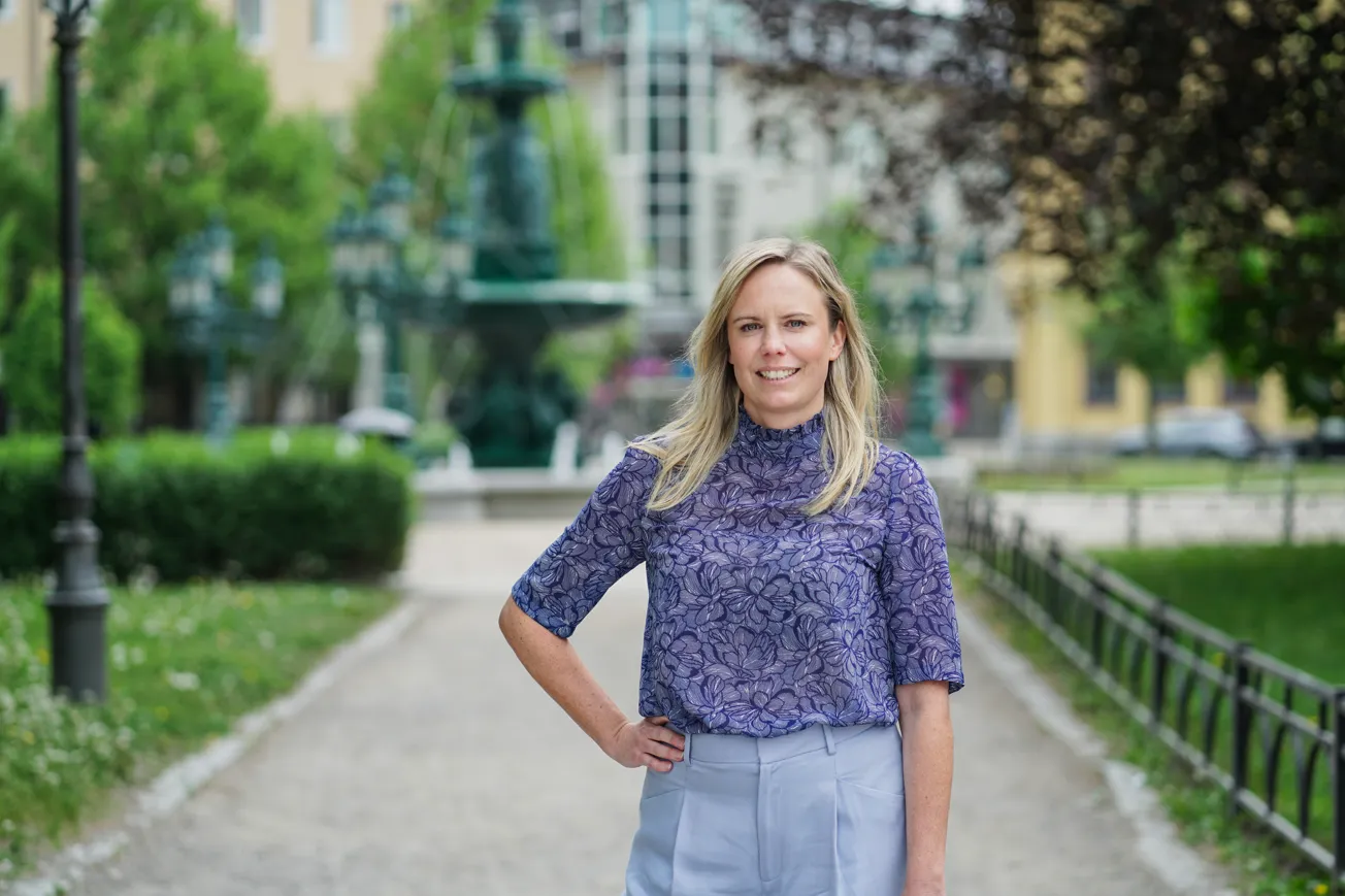 En kvinna som står i en park med händerna på höfterna.