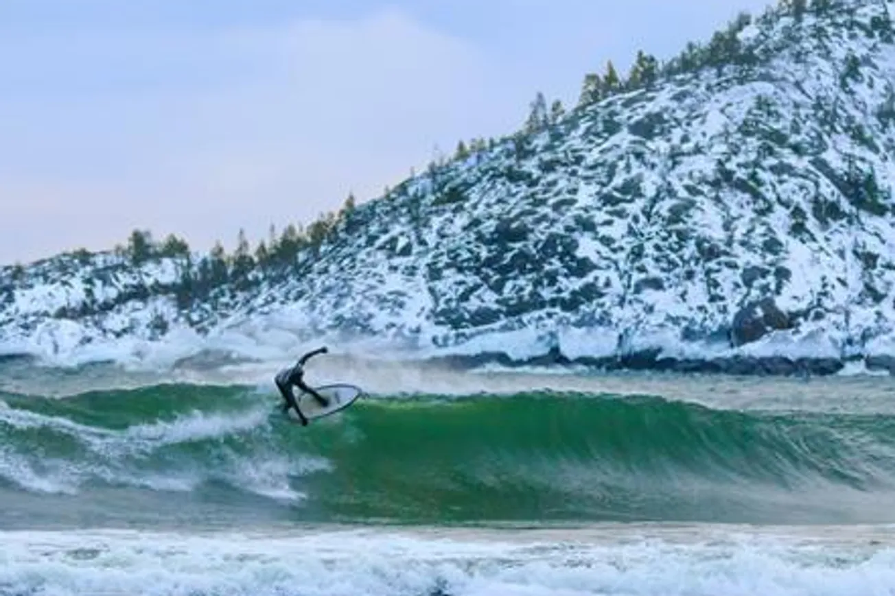 En man rider på en våg på en surfbräda.