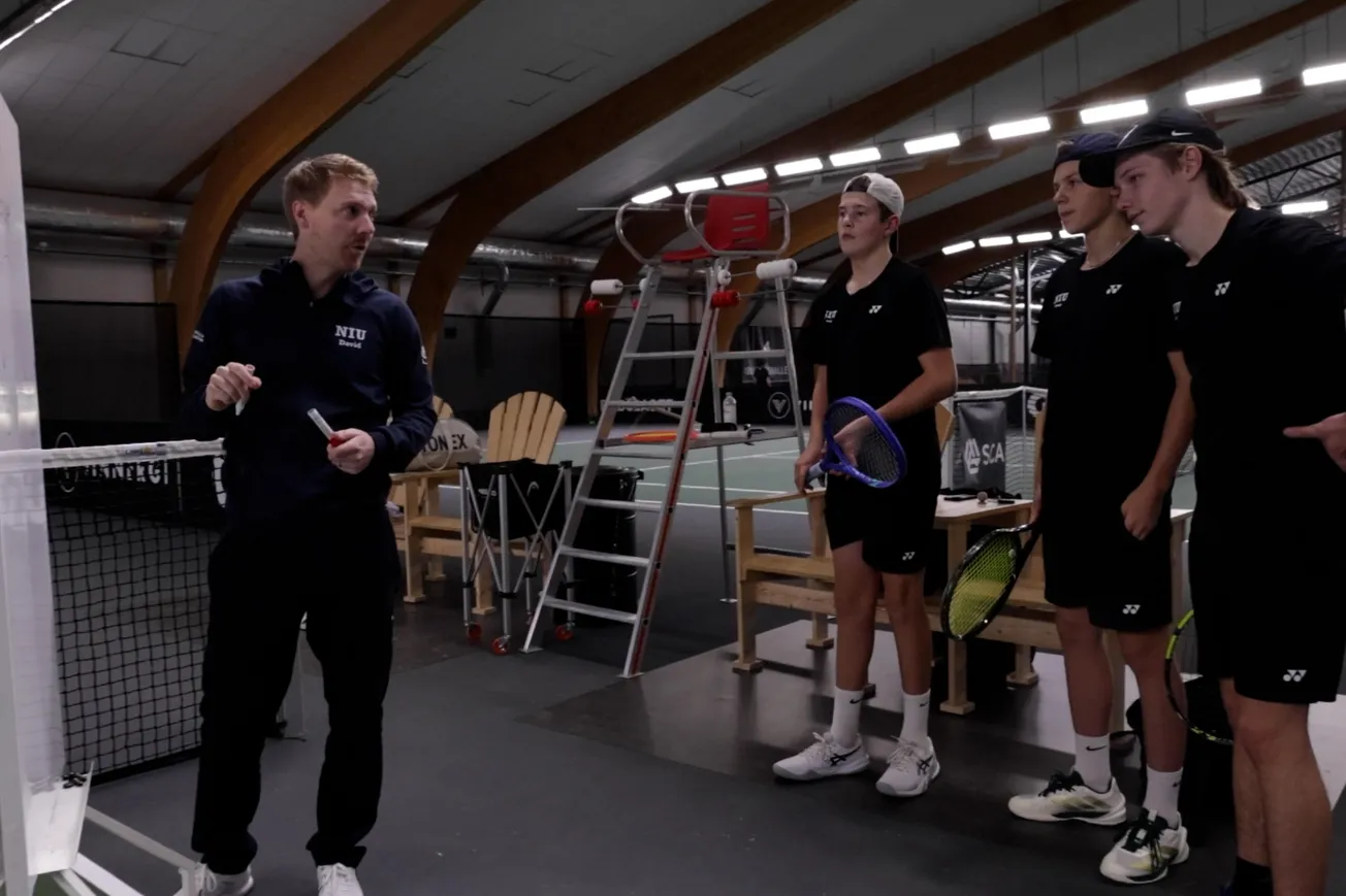 En grupp människor som står mitt på en tennisbana.