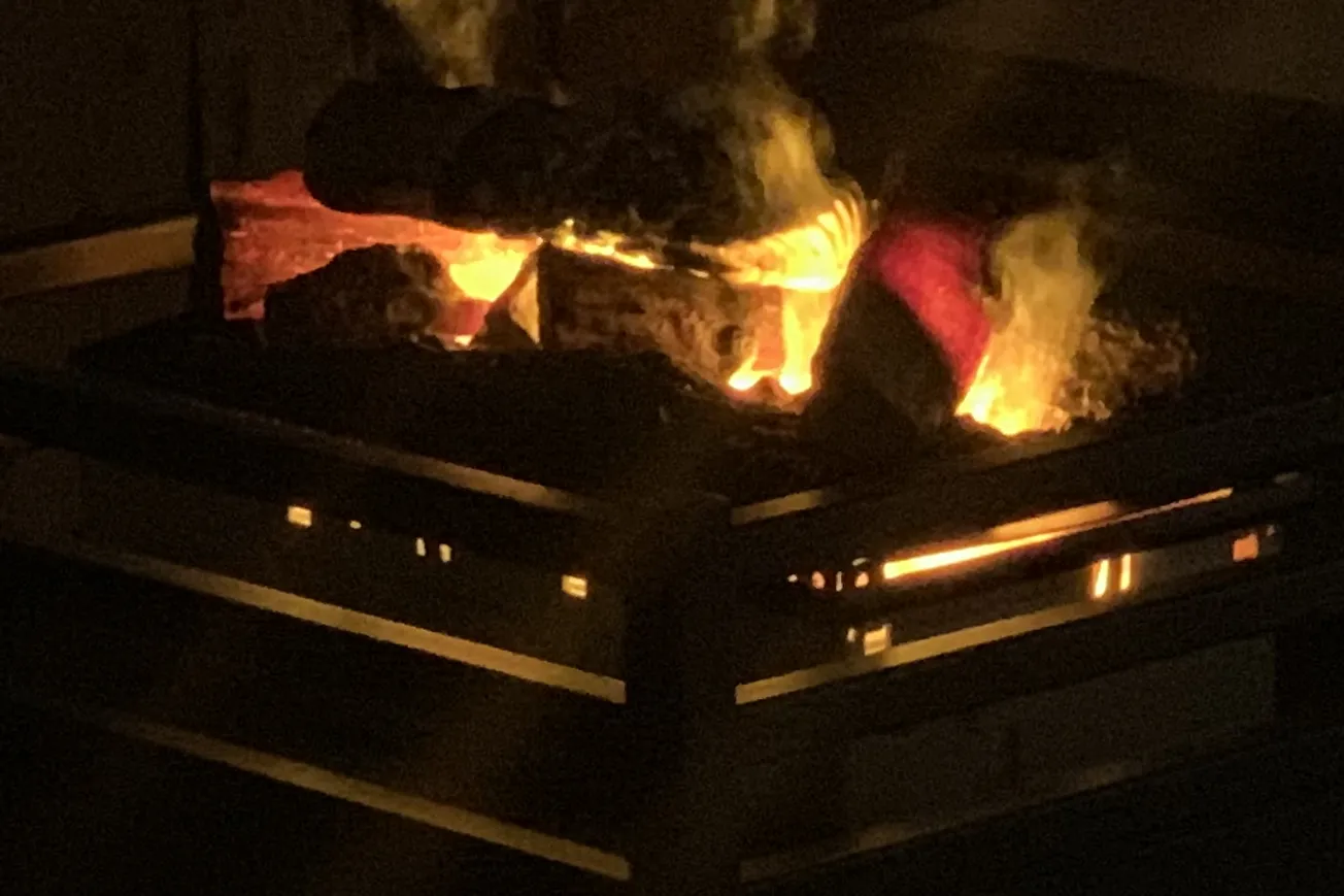 En eld som brinner i en öppen spis i ett mörkt rum.