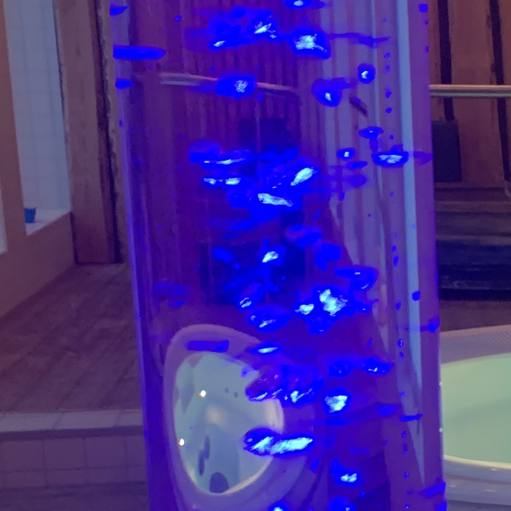 Ett jacuzzibadkar och en lavalampa med blått ljus vid sidan av det.