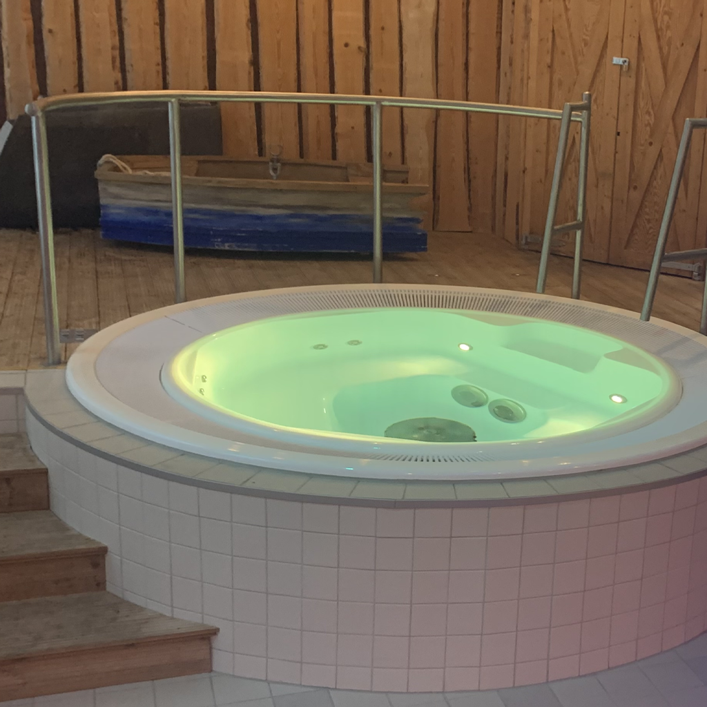 Ett stort jacuzzibadkar som sitter på ett klinkergolv.