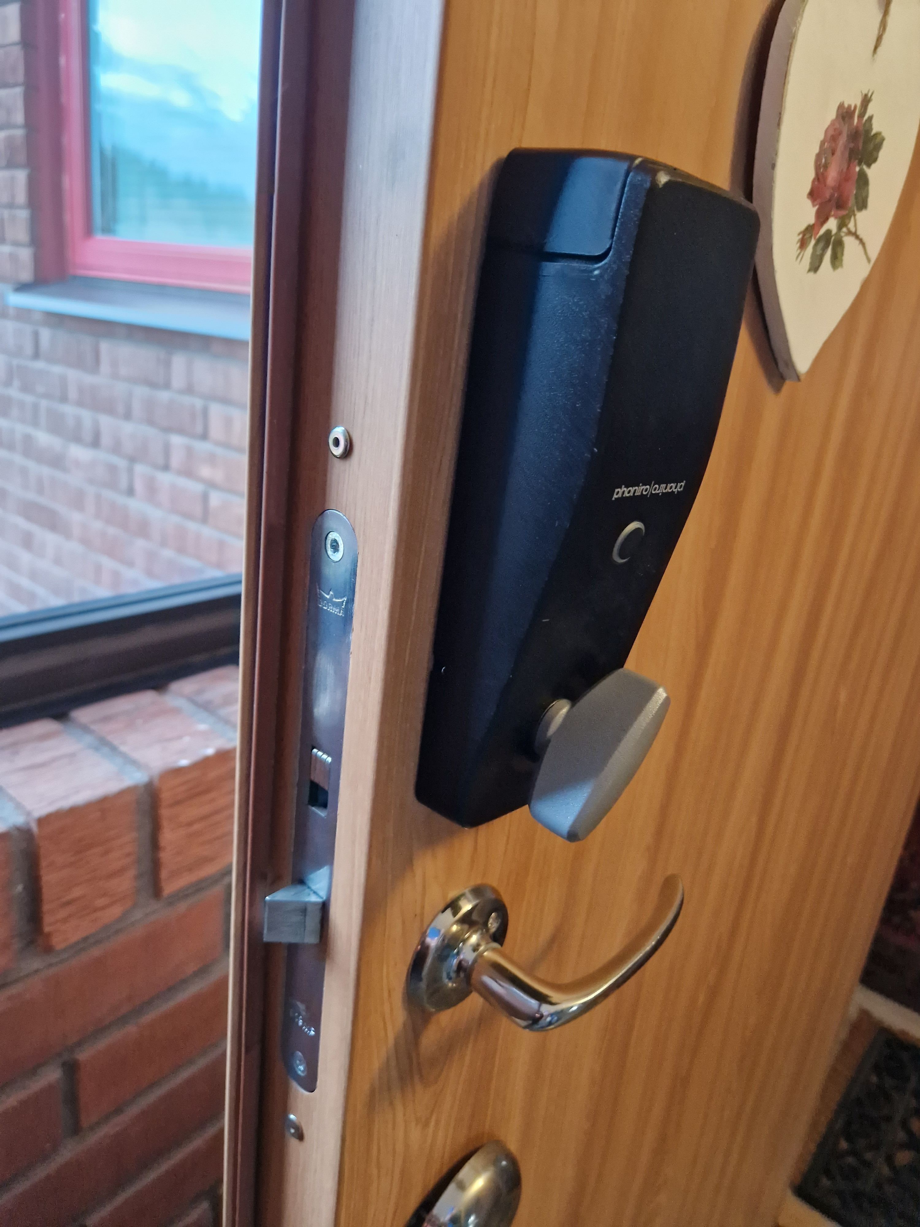 Ett dörrhandtag på en trädörr med en tegelvägg i bakgrunden.