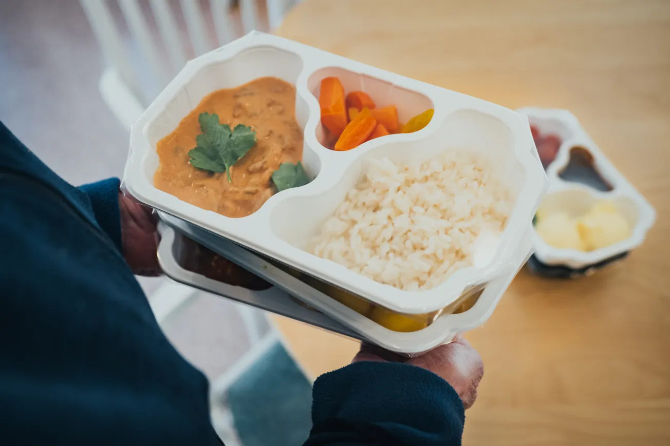 Händer som håller i tre matlådor staplade på varandra
