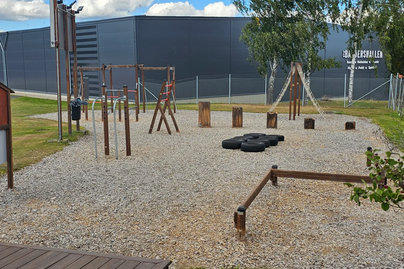 Träningsredskap utomhus sommar, i bakgrunden en stor byggnad.