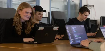 En grupp människor som sitter vid ett bord med bärbara datorer.
