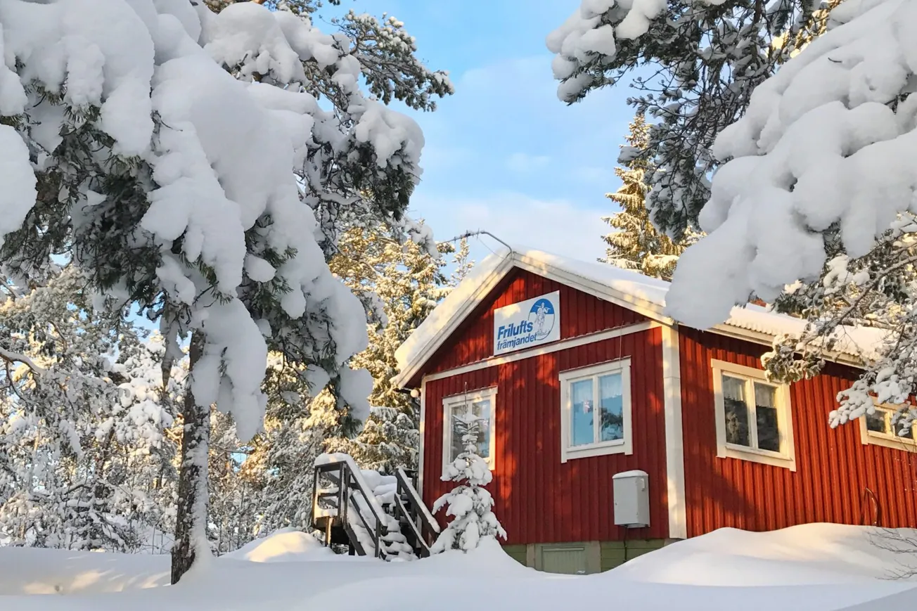 Röd stuga i vintermiljö.