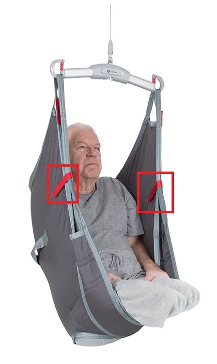 En man som genomgått amputation sitter i en lyftsele av modellen AmpSling. Selens styröglor är markerade med röda rektanglar.