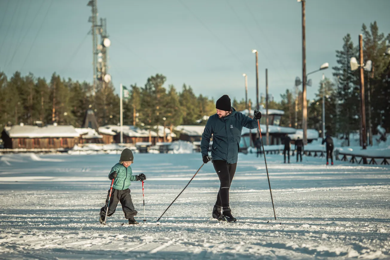 En kvinna och ett barn på skidor i snön.