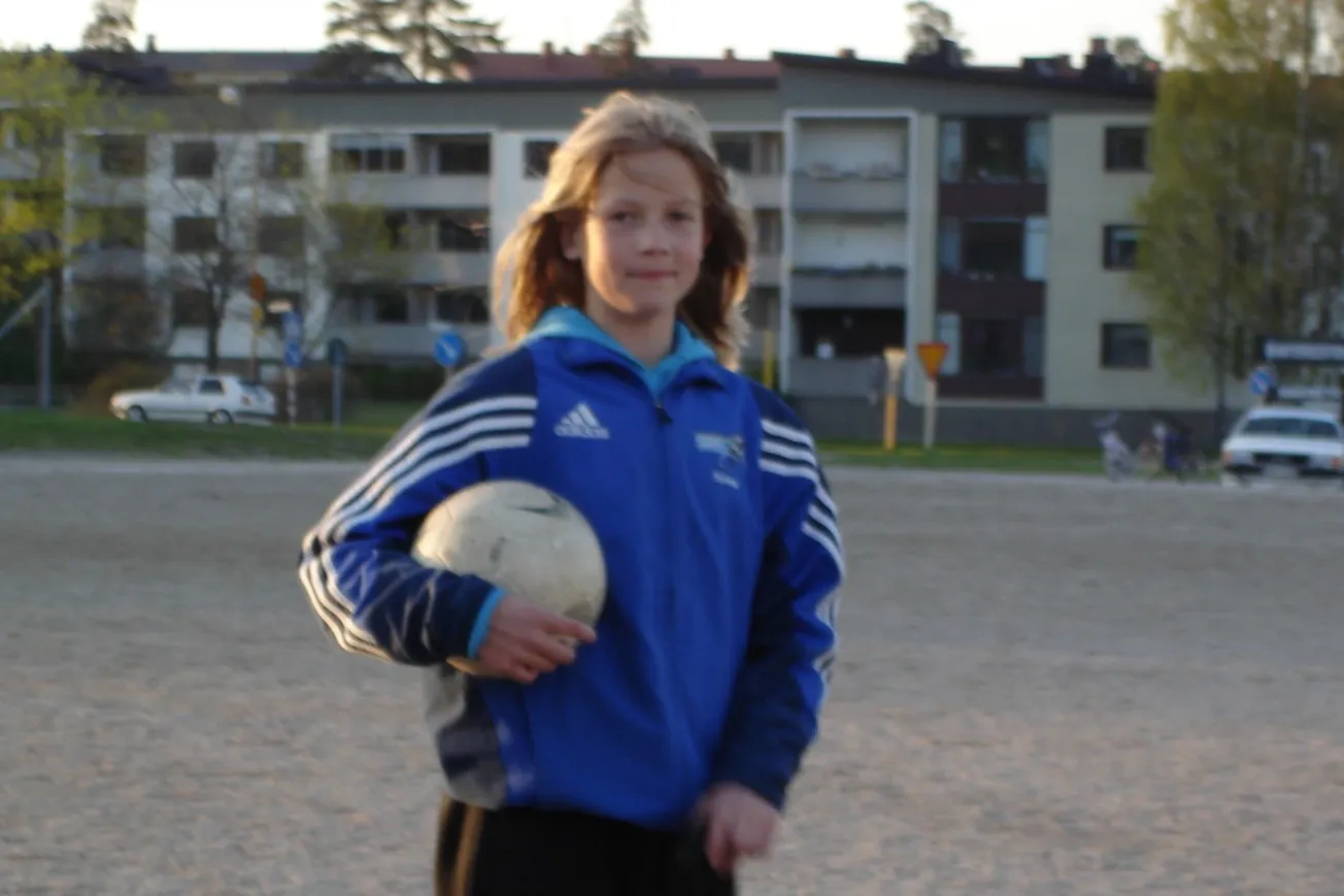 En ung flicka håller i en fotboll.