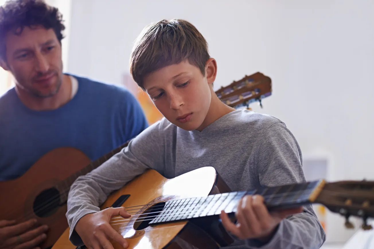 En man och en ung pojke spelar gitarr.