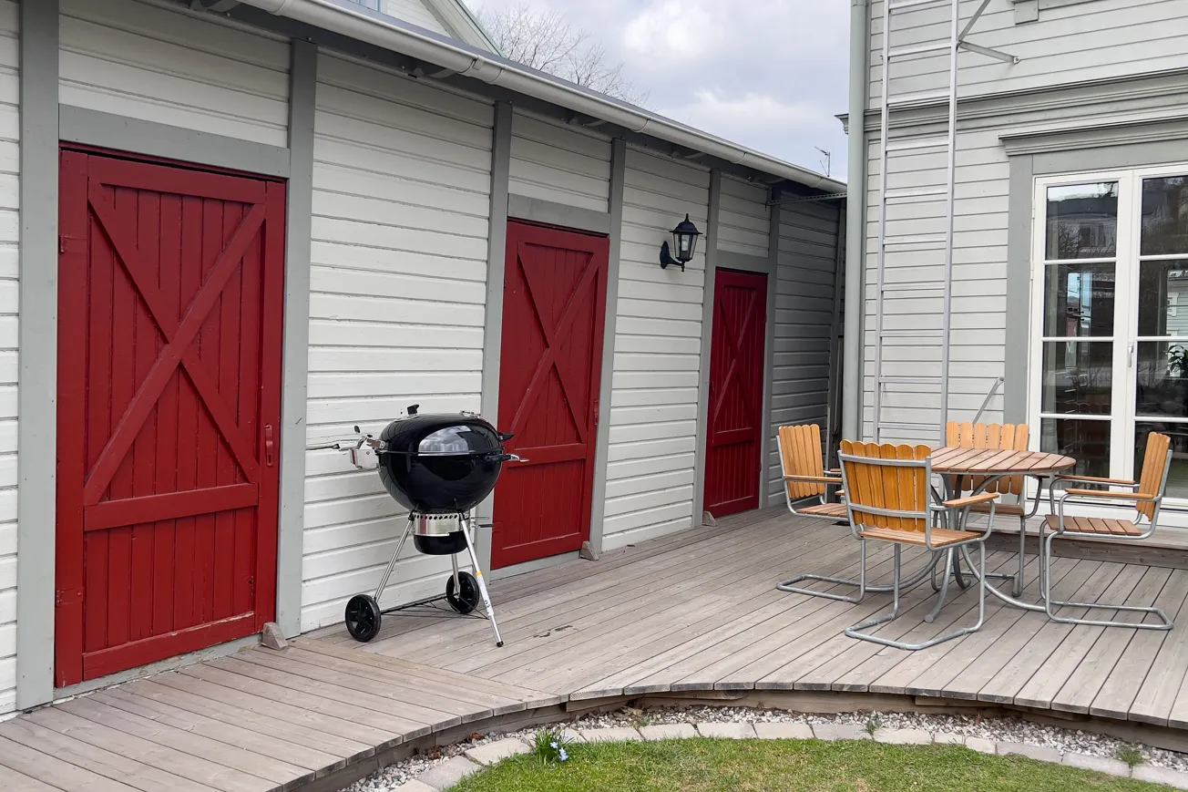 En bbq-grill på ett trädäck intill en hus.