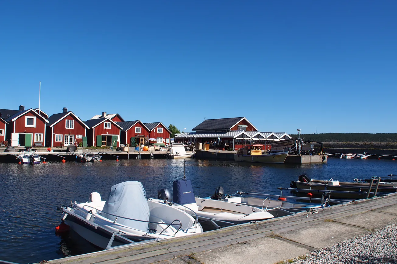 En rad röda hus som ligger intill ett vattendrag med små båtar.