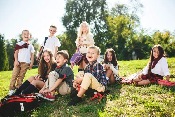 En grupp skolbarn som sitter på en grön äng.