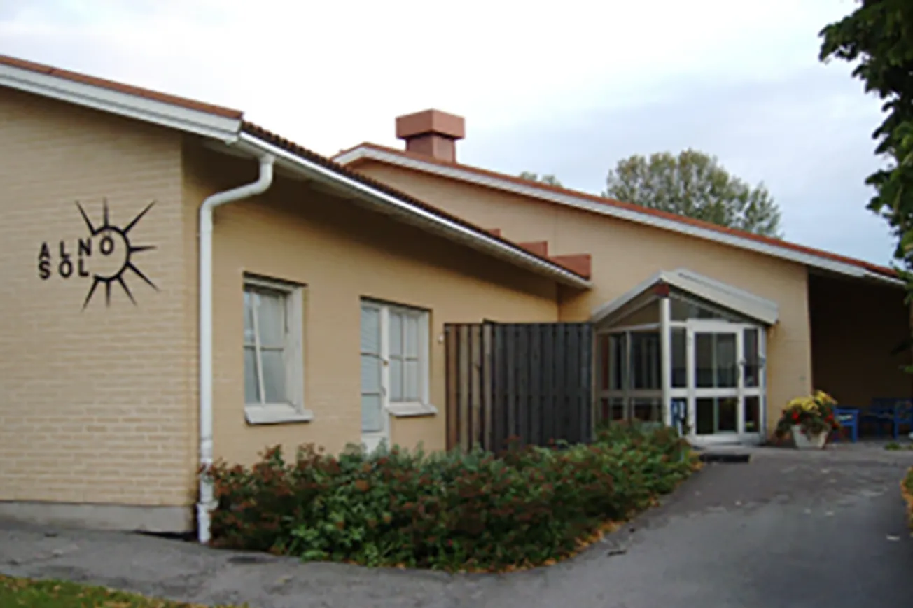 En byggnad med gul fasad och texten Alnösol.