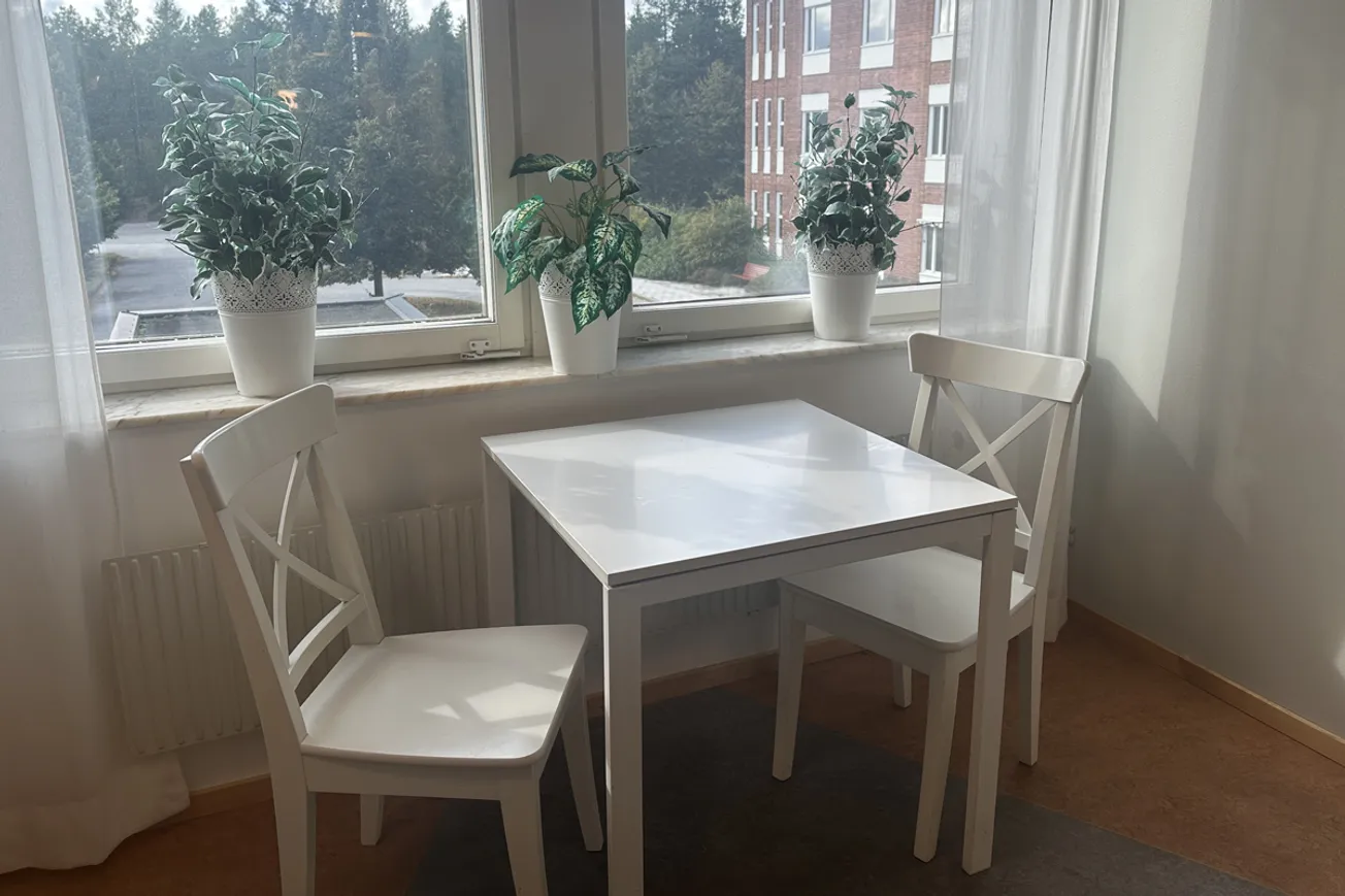 Ett bord och två stolar framför ett fönster.