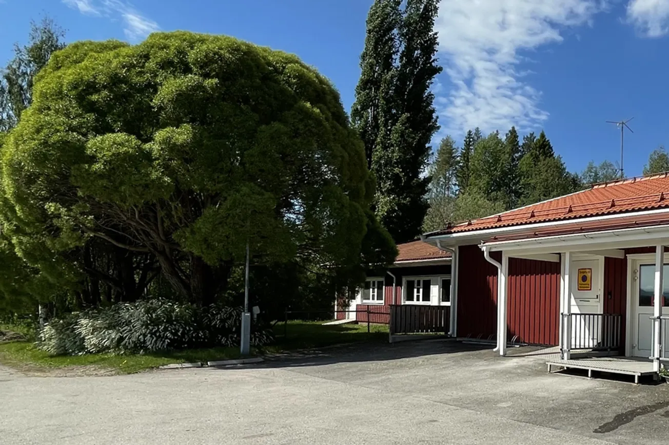 En röd byggnad med rött tak och ett vitt staket.