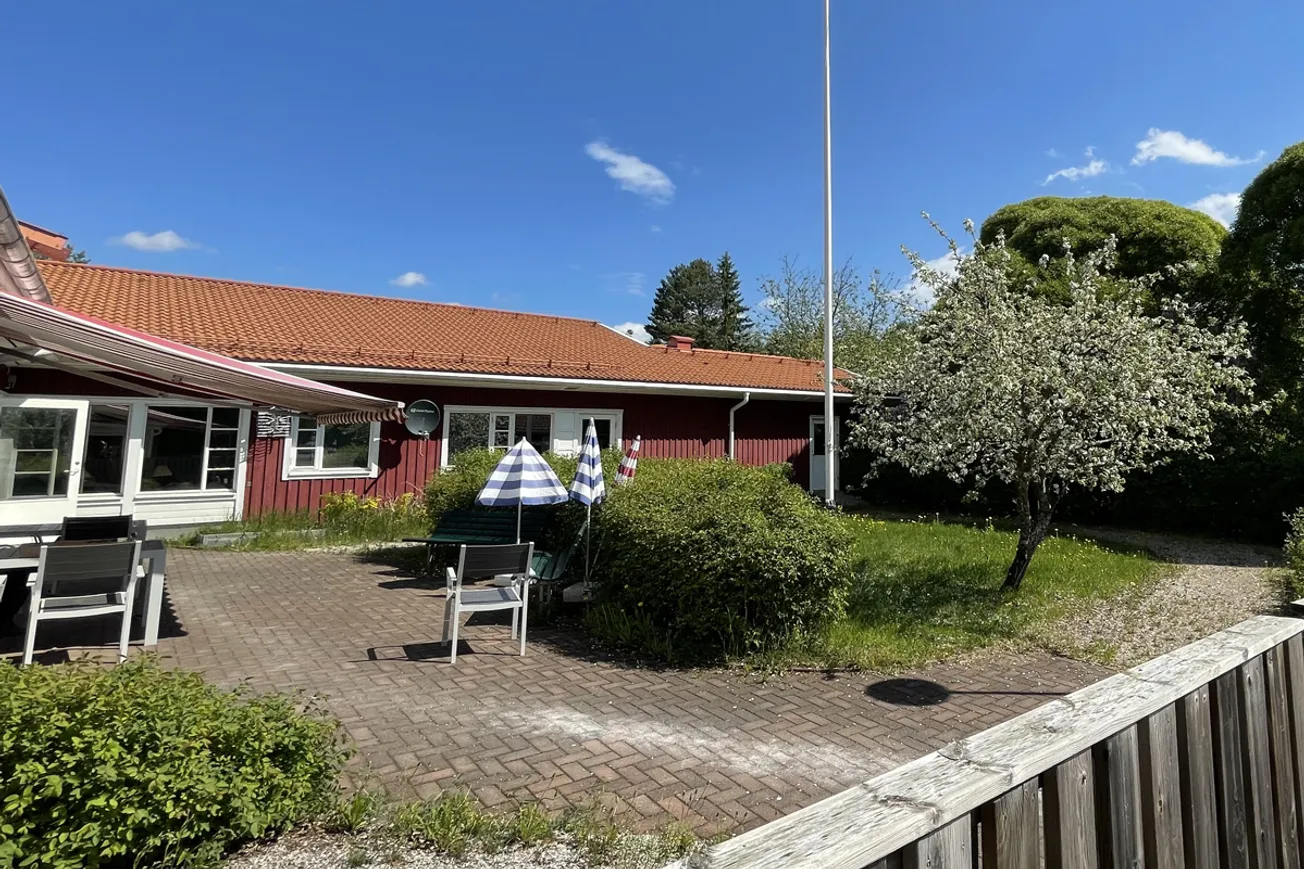 En uteplats med bord och stolar intill ett staket.