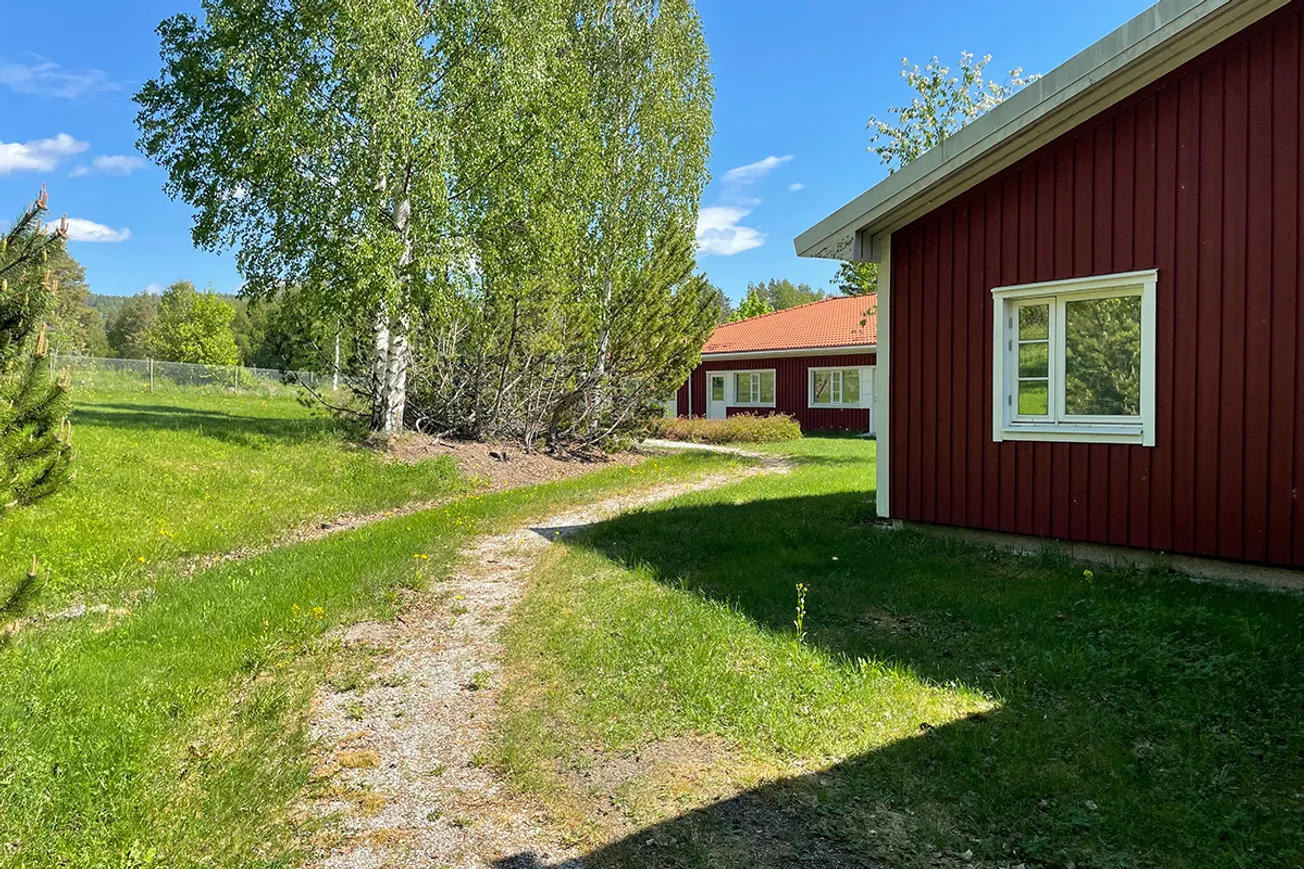 En röd byggnad med en grusväg som leder fram till den.