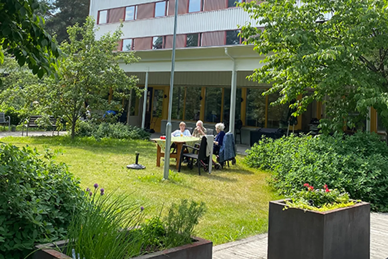 En grupp människor som sitter vid ett bord utanför en byggnad.