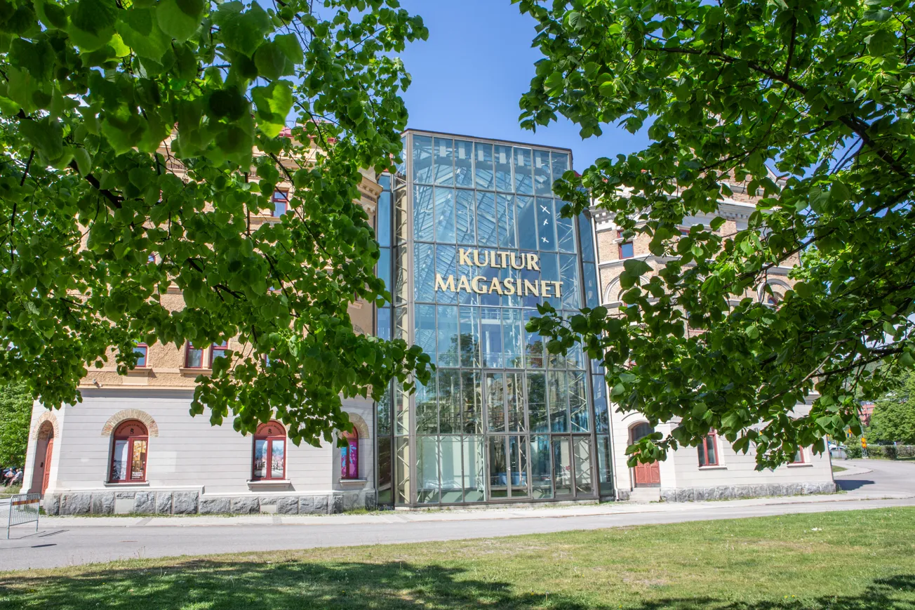 Kulturmagasinets östra fasad skymtar bland trädgrenarna.