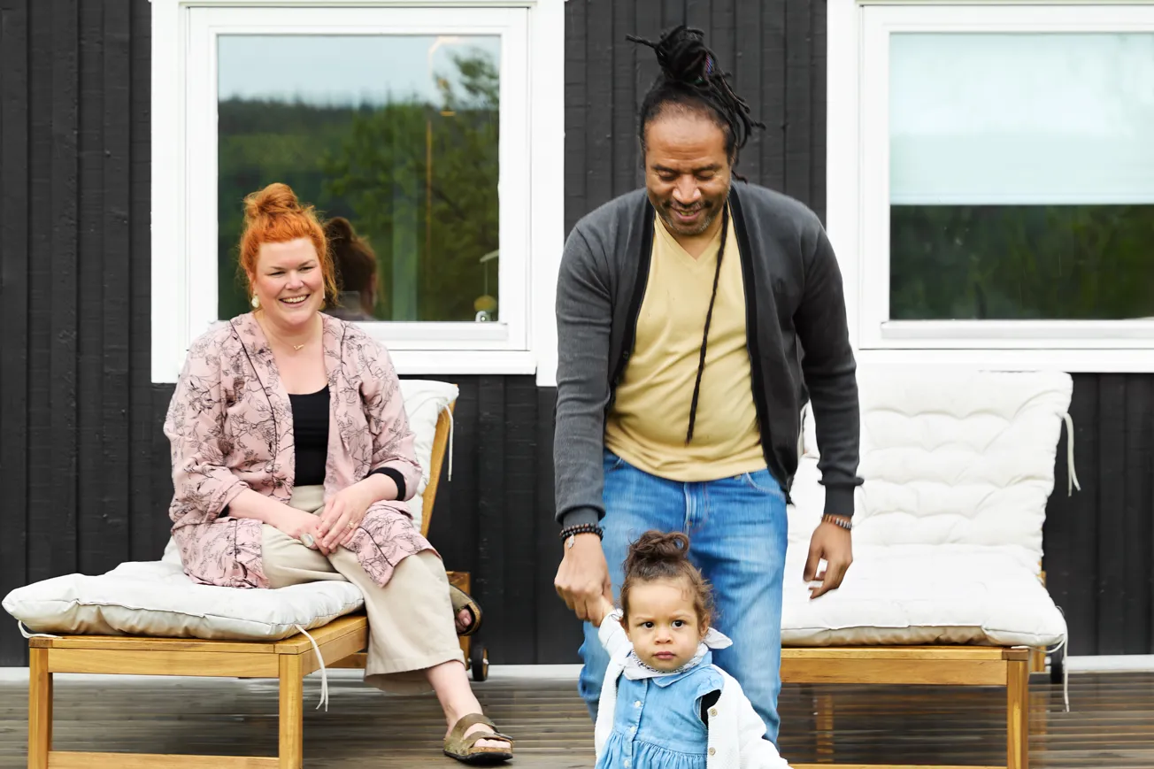 En man och en kvinna som står på en veranda med ett barn.