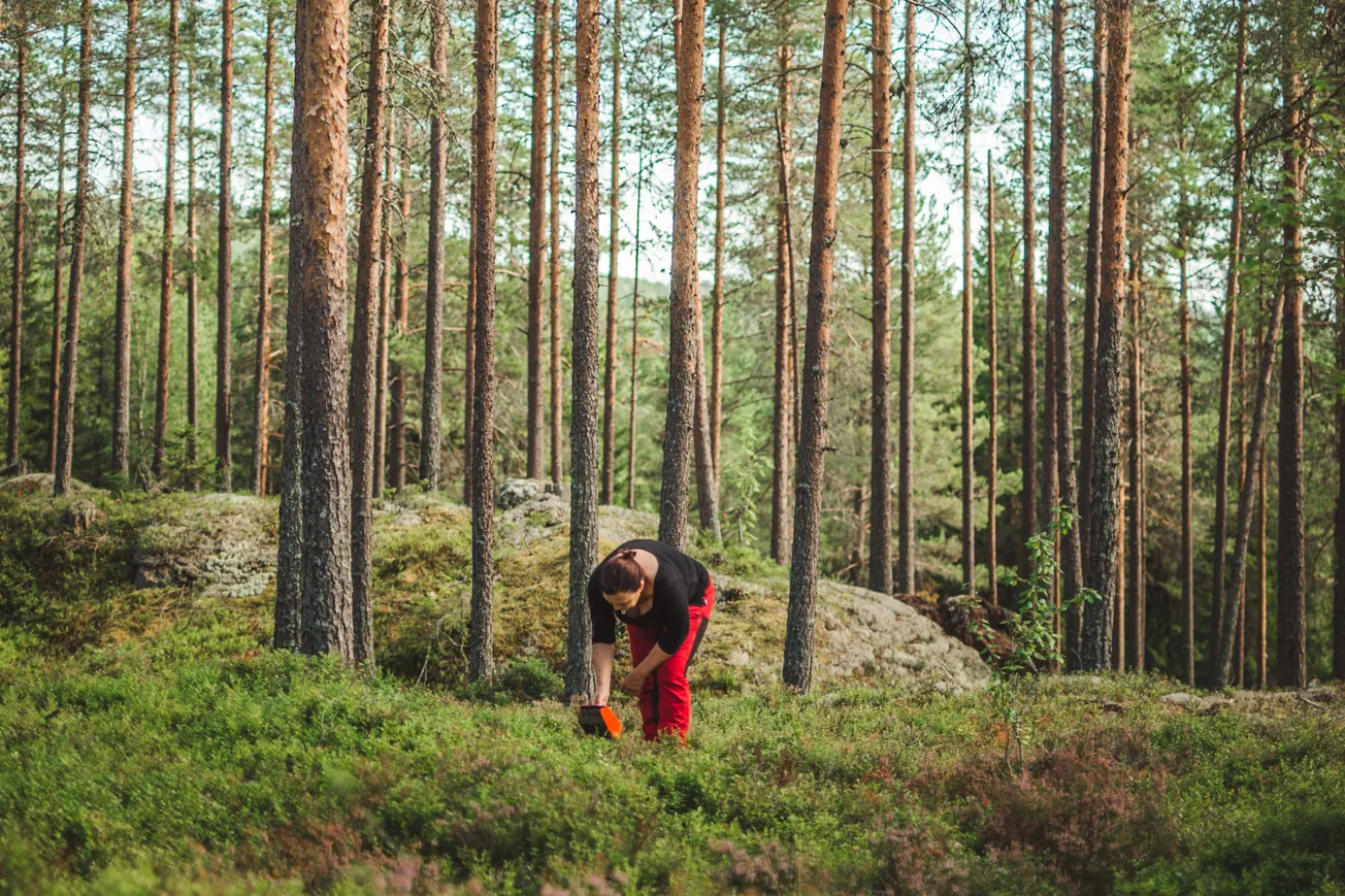 En kvinna som står mitt i skogen.