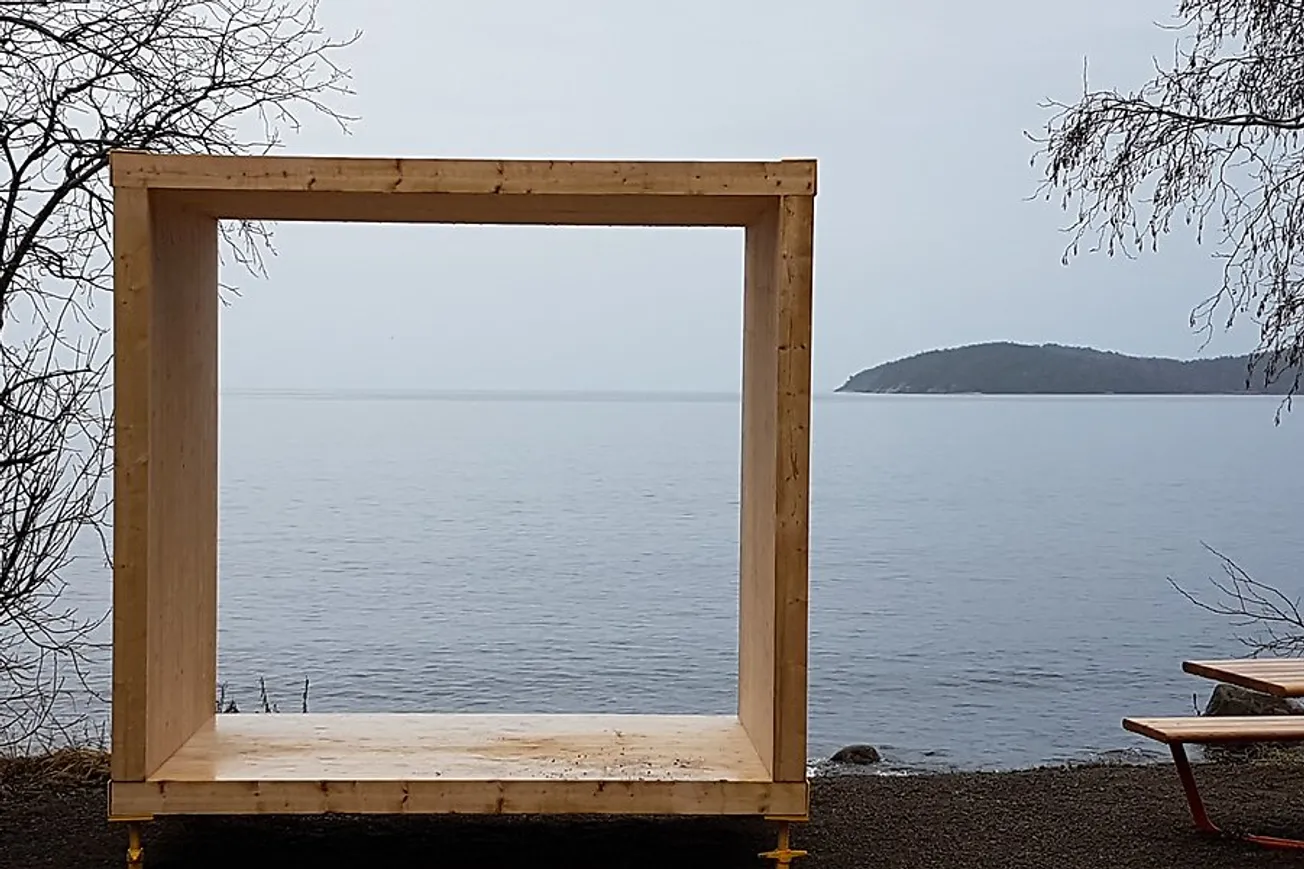 Ett konstverk i form av en träram vid stranden där havet syns bakom ramen.