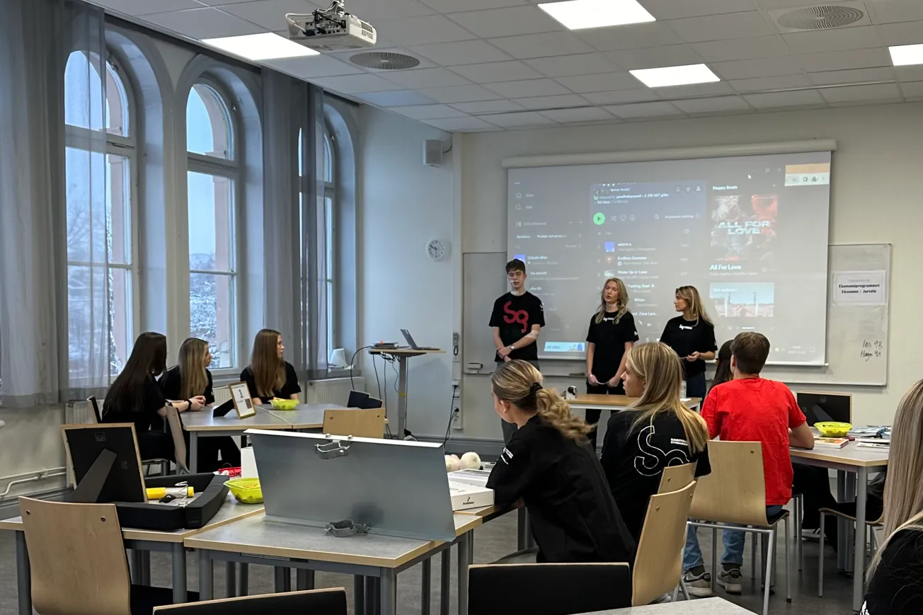 En grupp människor i ett rum med en projektorduk.