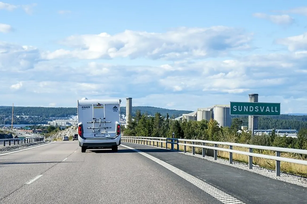 En husbil kör på en motorväg bredvid en motorvägsskylt.