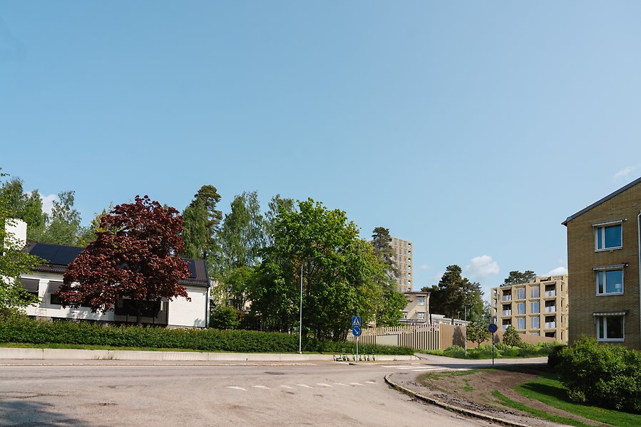 Illustration av byggnad i gult tegel bredvid andra byggnader och hus.