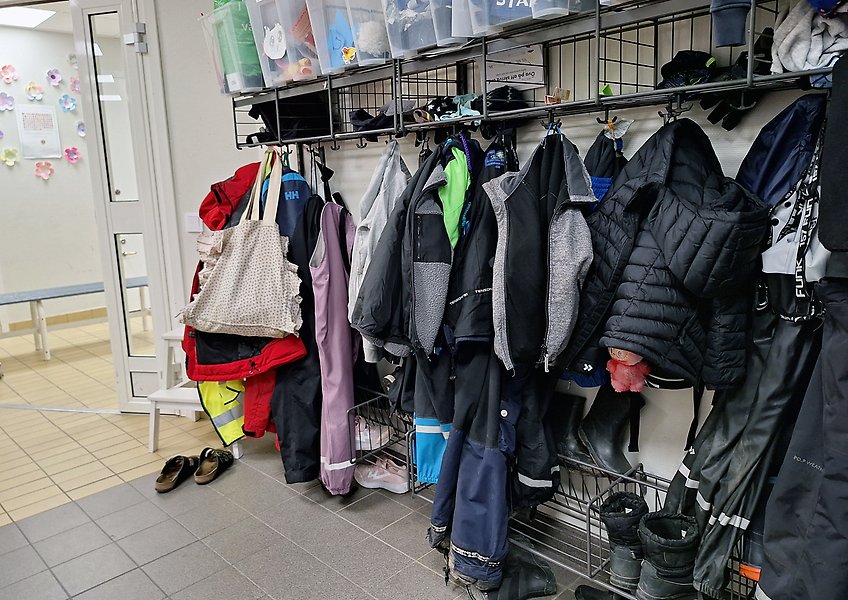 En skolhall med väggmonterade klädhängare och jackor, väskor och stövlar.