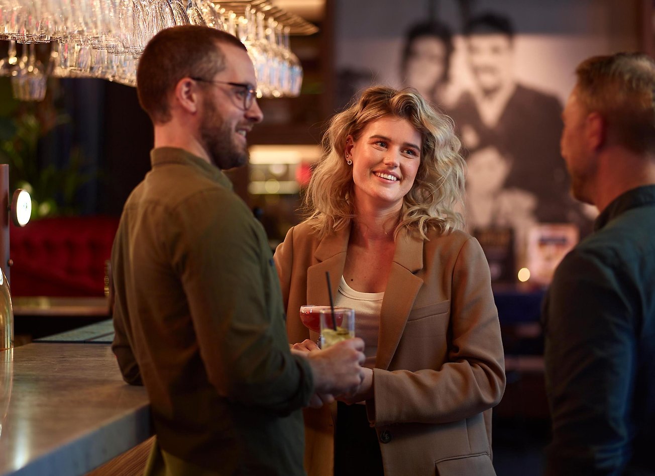 Tre personer som står vid en bar och pratar. Fotograf: Kristofer Lönnå Produktion AB