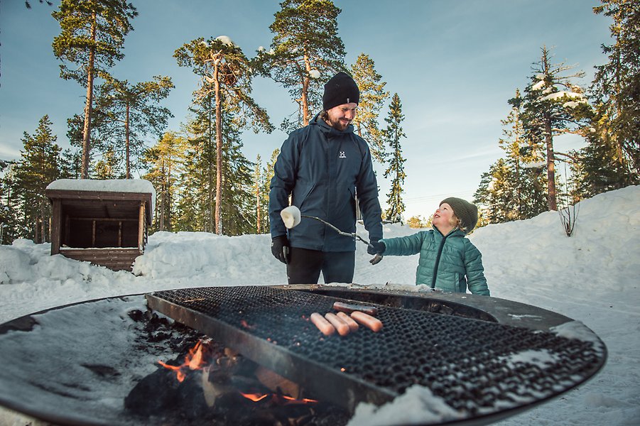 Korvgrillning vinter på Södra berget vid en nsöklädd grillplats.