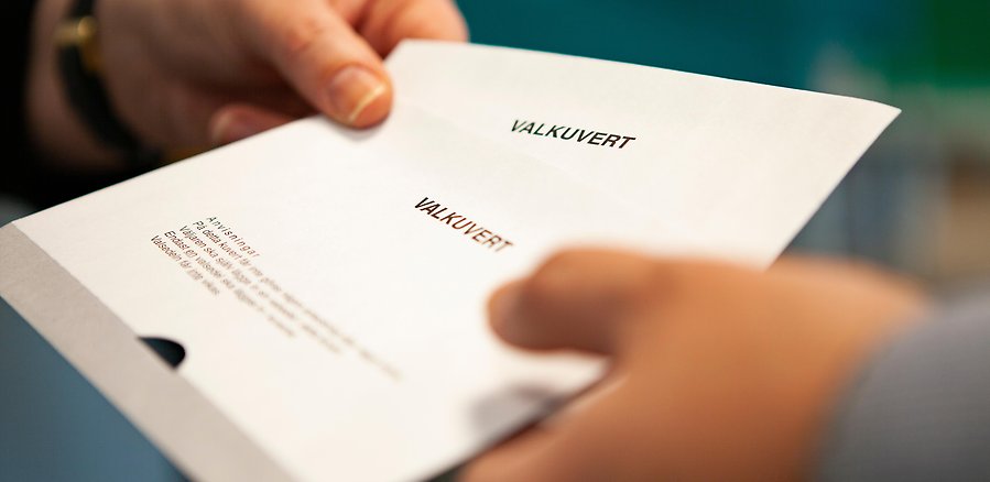 Röstmottagare ger ut valkuvert till väljare.
