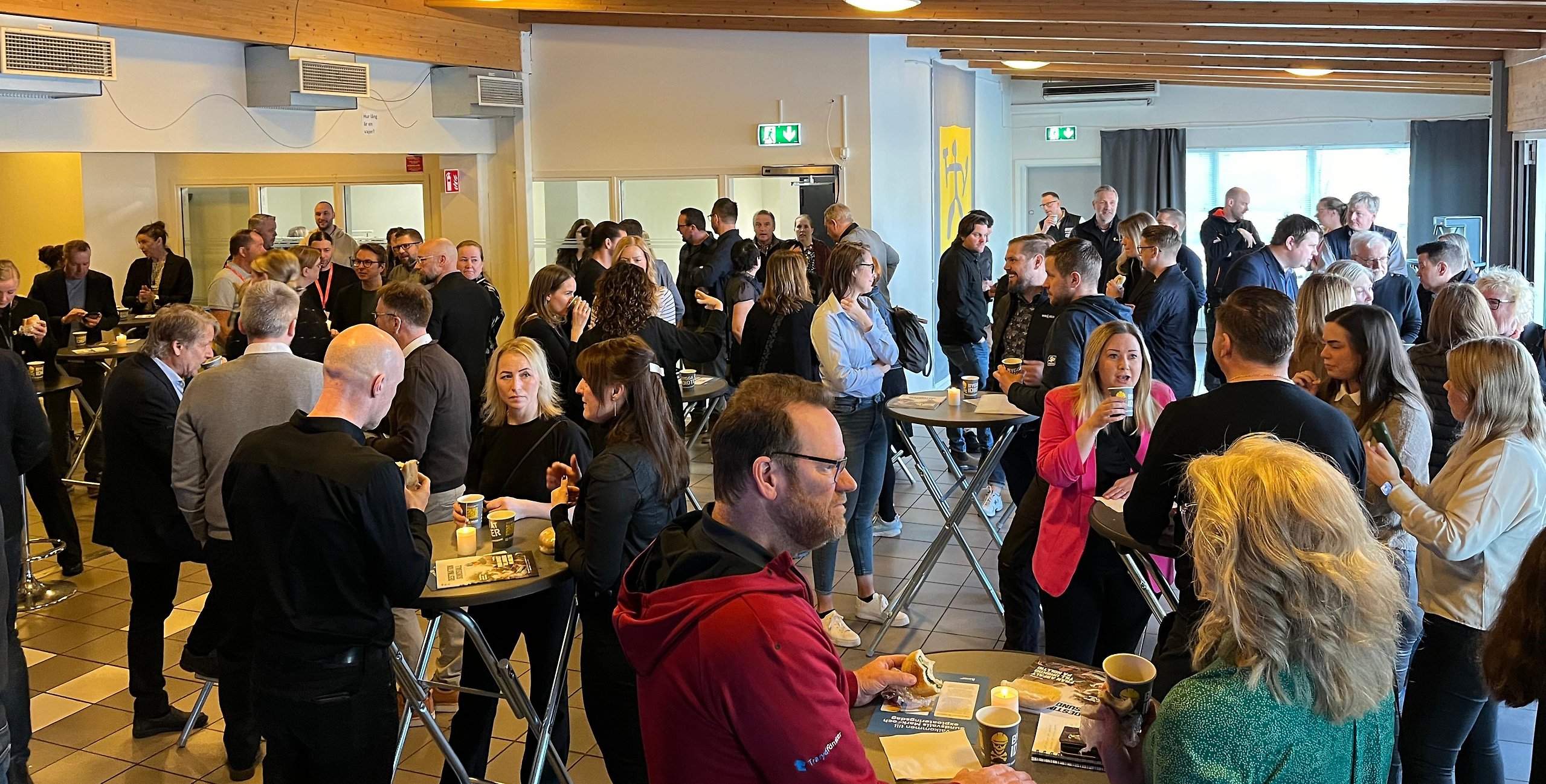 En grupp människor samtalar i en lokal under en frukost