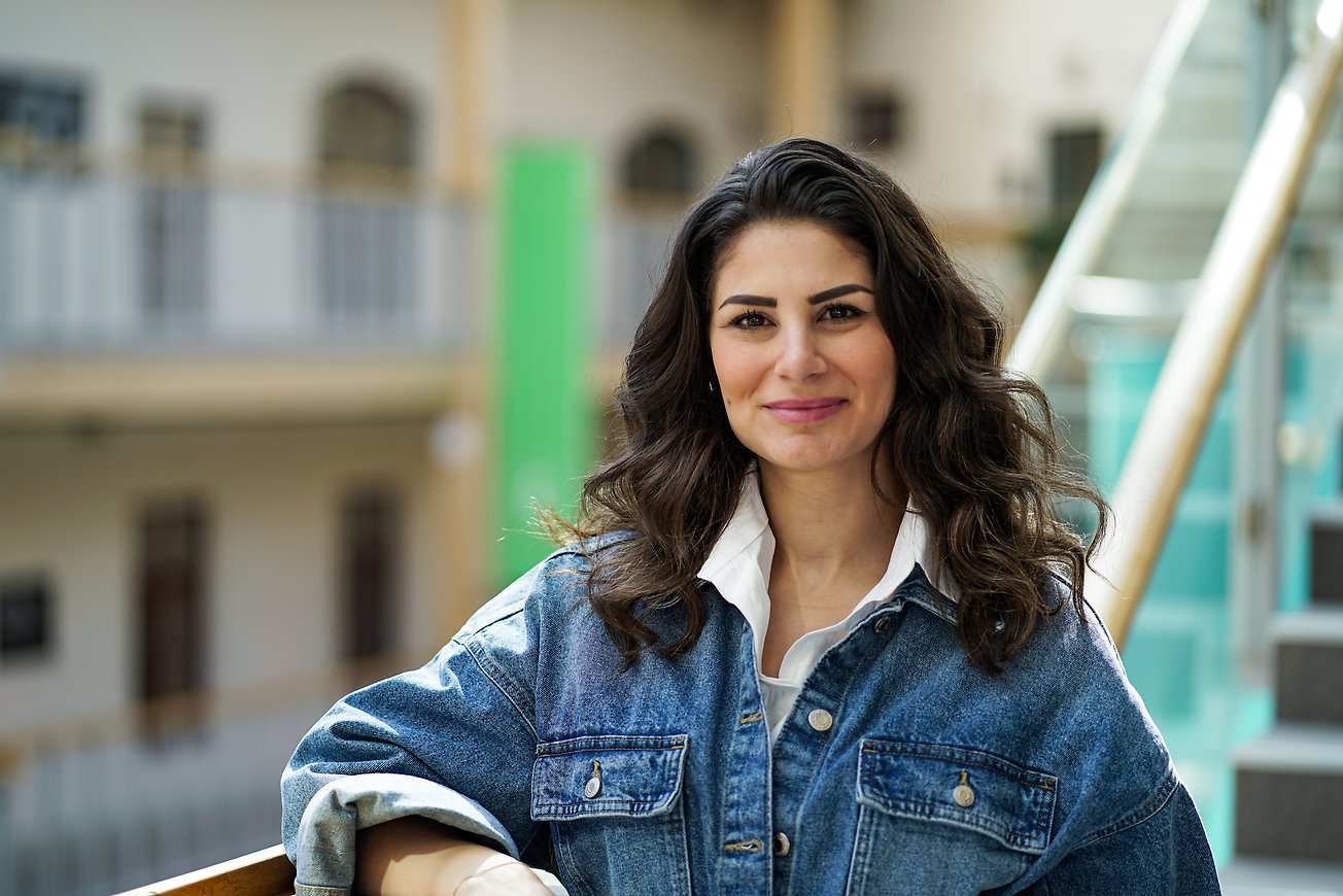 Giselle Abbas står vid en trapp och tittar in i kameran