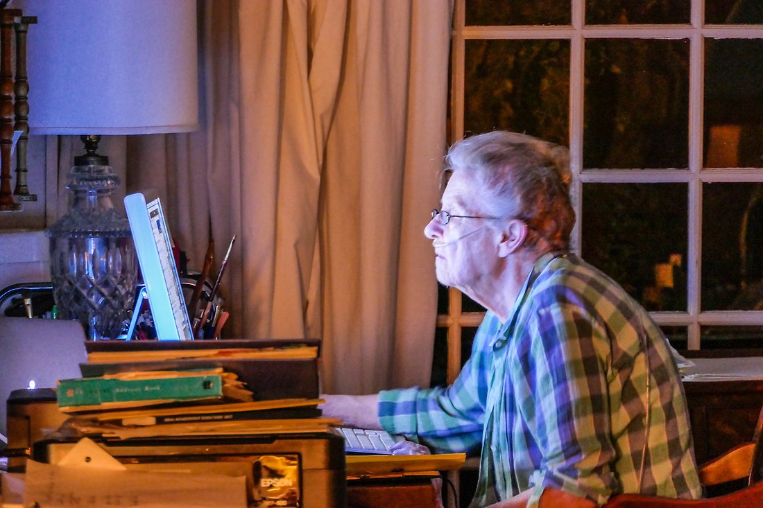 En äldre personer sitter framför en dator och arbetar.